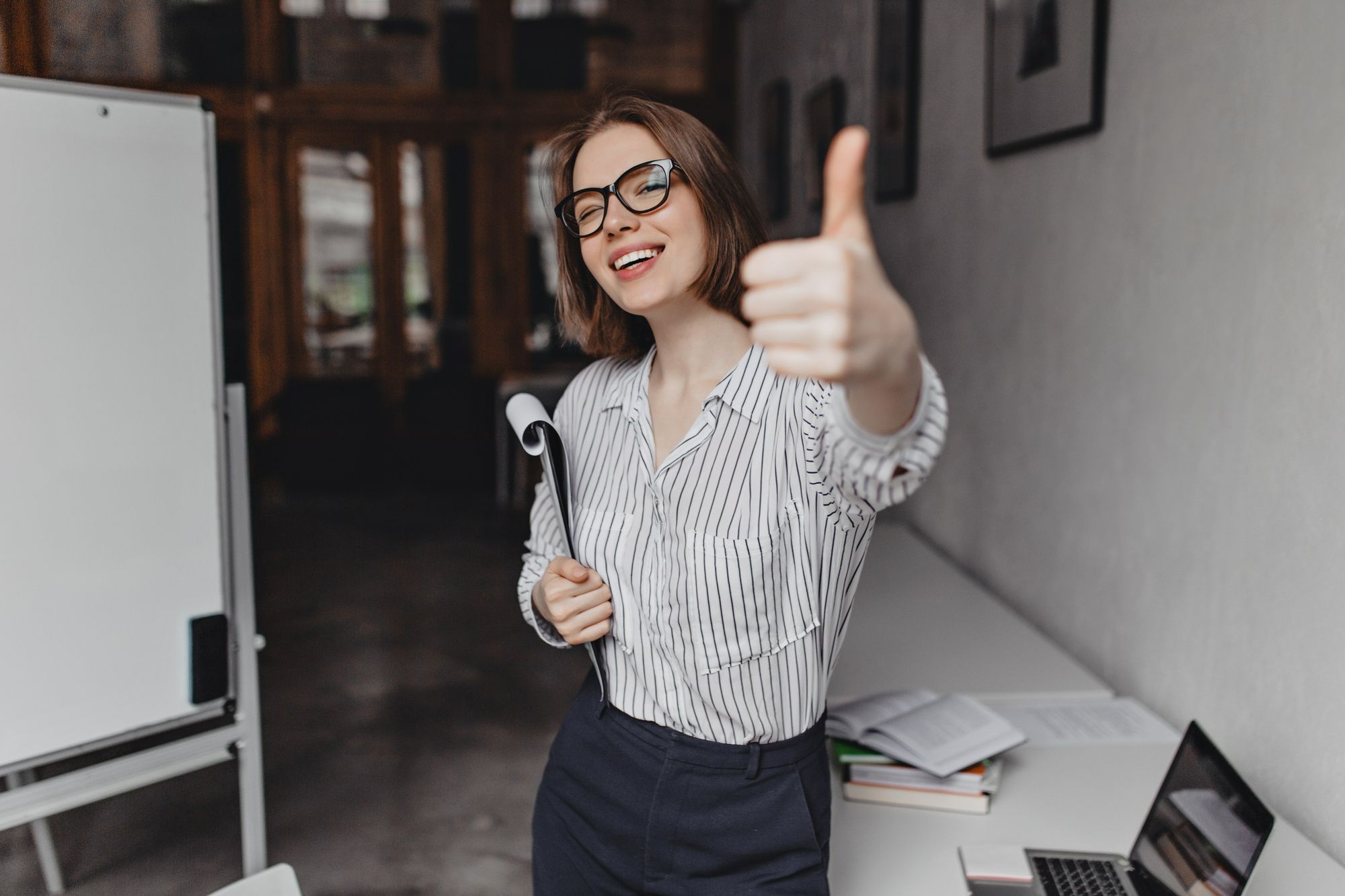 Profissional sorridente fazendo sinal de positivo em ambiente de trabalho, o que simboliza os benefícios da gamificação na hotelaria para o engajamento da equipe e fortalecimento da cultura organizacional.