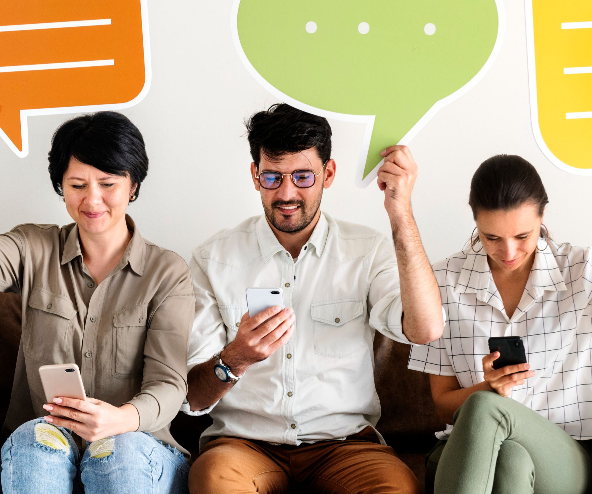 Três pessoas usando seus celulares enquanto interagem com balões de fala coloridos, ilustrando como a gamificação na hotelaria pode aumentar o engajamento do público em eventos por meio de atividades interativas como quizzes.