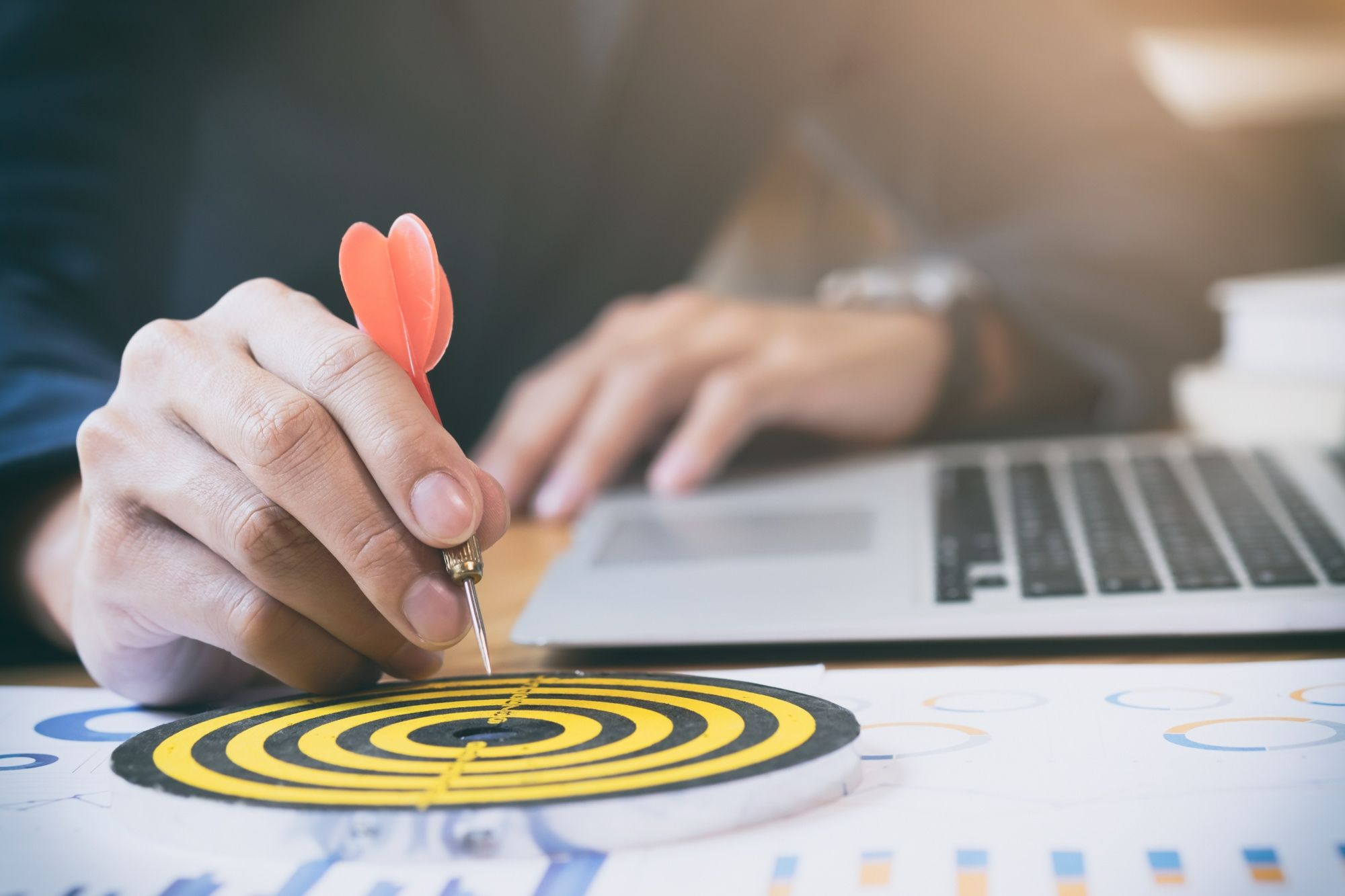 Mão segurando dardo e mirando o centro de um alvo, simbolizando o foco estratégico no SEO para sites de hotéis