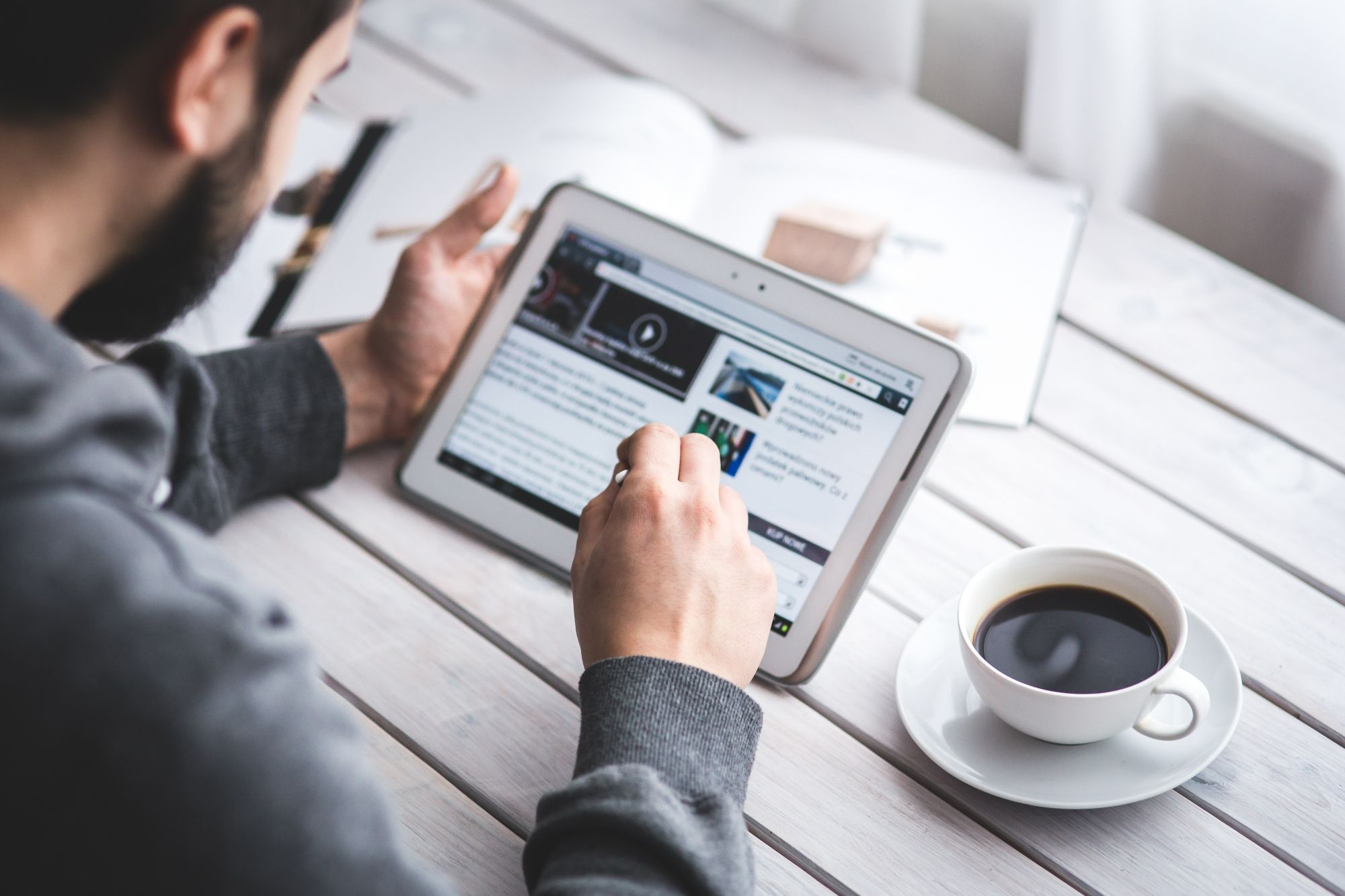 Pessoa navegando em site de notícias em um tablet, simbolizando práticas de SEO para sites de hotéis em dispositivos móveis