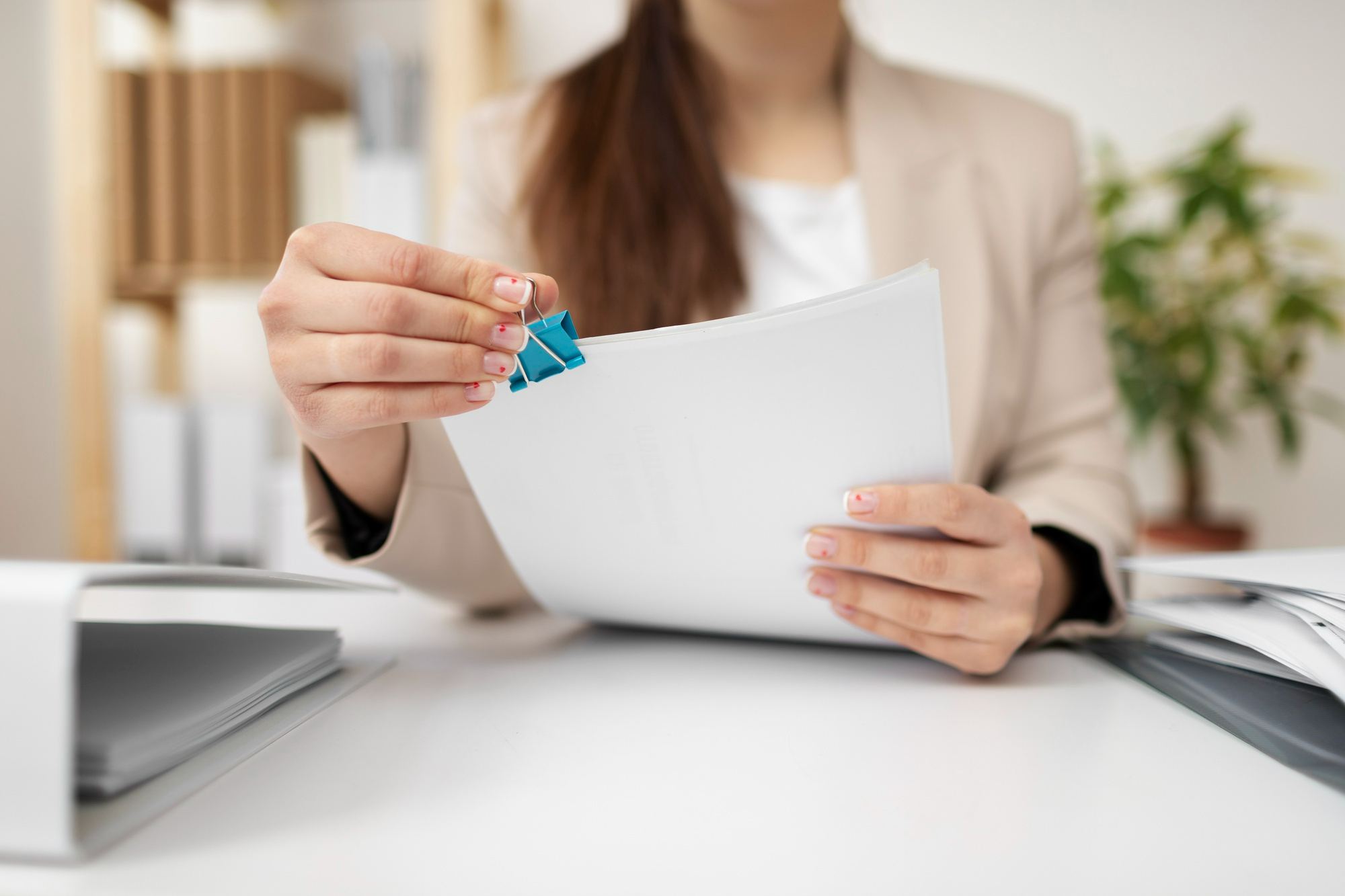 Pessoa organizando documentos com clipe de papel, representando a importância da preparação e análise de dados antes de iniciar processos de compras para hotéis.