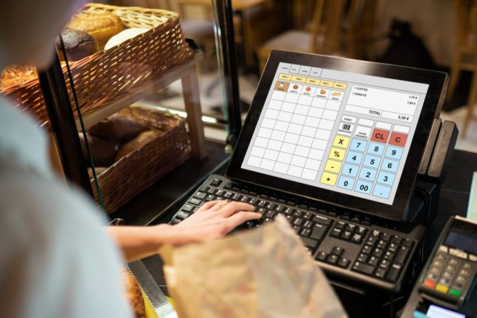 Funcionário registra venda em sistema de caixa moderno, ilustrando práticas eficientes de controle e atendimento para quem busca saber como aumentar a receita do restaurante do hotel.