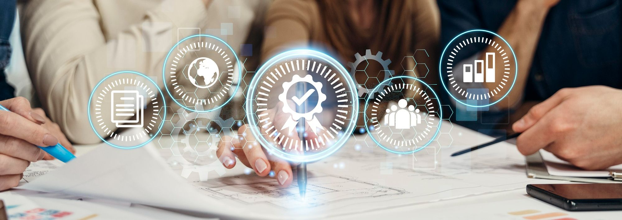 Profissionais reunidos em mesa de trabalho analisam documentos e gráficos, com ícones digitais de qualidade, desempenho e pessoas sobrepostos. A foto ilustra como uma estrutura de governança hoteleira contribui para a tomada de decisões estratégicas, inclusive no que se refere ao controle e à prevenção de riscos.