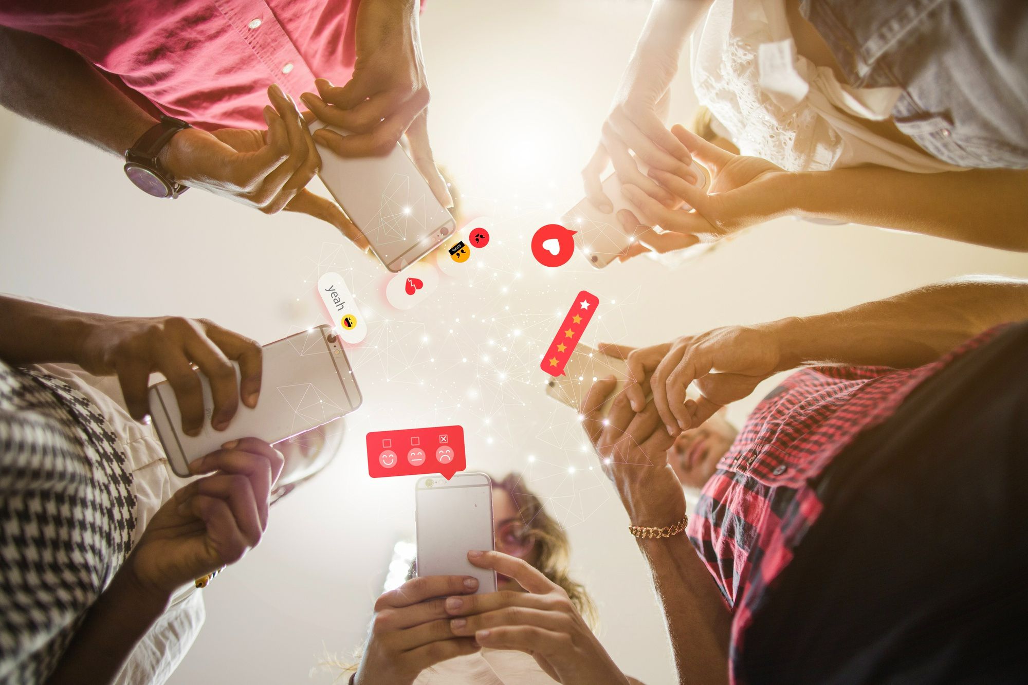 Grupo de pessoas visto de baixo, interagindo com seus smartphones, com ícones digitais de curtidas, comentários, avaliações e emojis flutuando no ar. A cena representa o engajamento online como uma métrica valiosa na avaliação de eventos em hotéis, ressaltando a importância da reputação digital e da percepção da marca.
