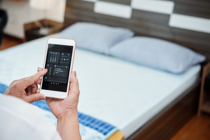 Pessoa usa smartphone para controlar funções do quarto de hotel, ilustrando como a automação e a aplicação da tecnologia na hotelaria conseguem melhorar a experiência do hóspede.