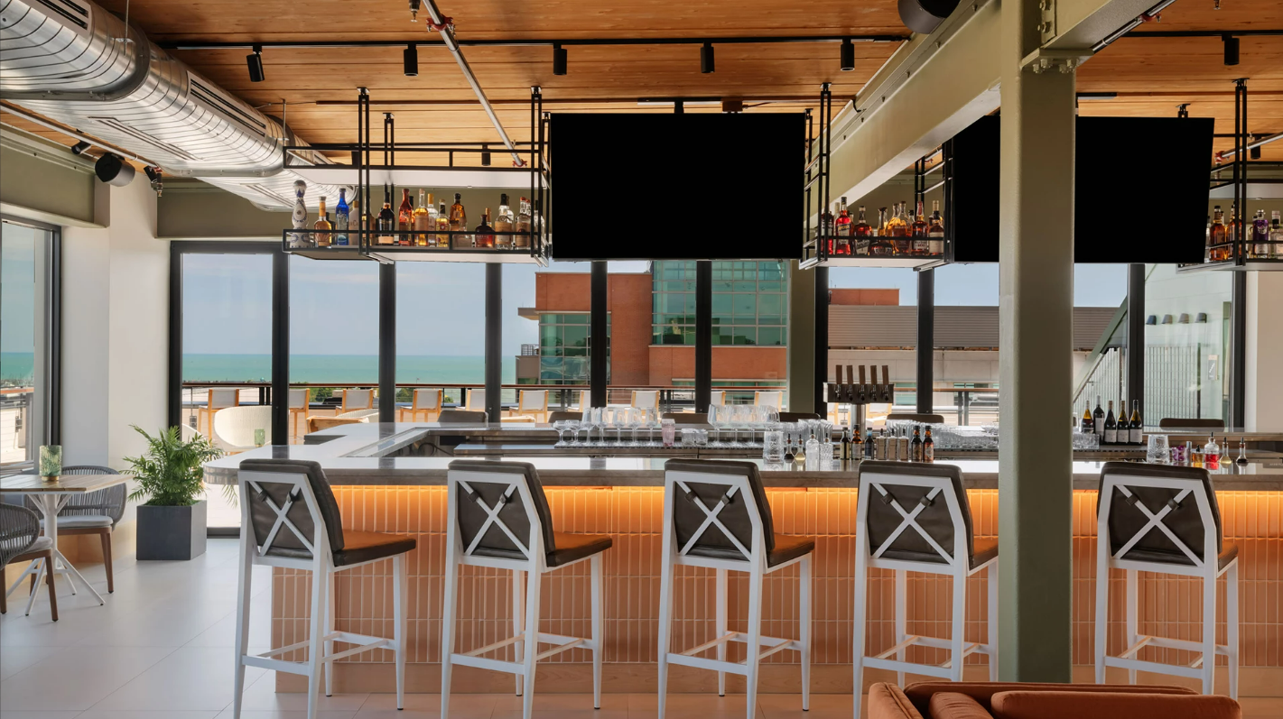 Bar moderno do Hotel Verdant com vista para o mar, exemplo de inovação tecnológica em hotéis com sensores que otimizam o uso de energia elétrica.