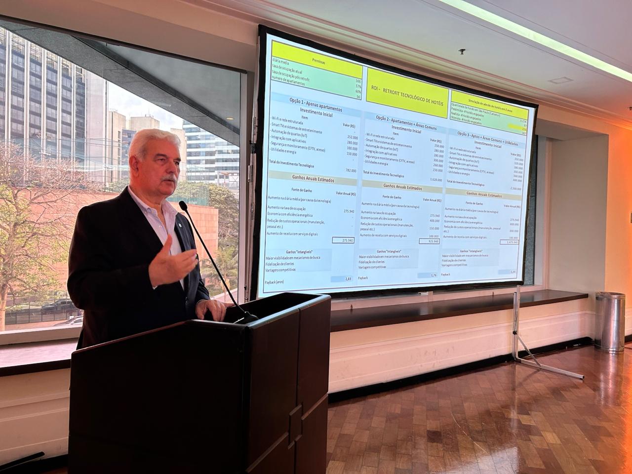 Walter Teixeira, head comercial do Portal do Hoteleiro, discursa em frente a uma apresentação detalhada com estimativas de retorno do investimento no projeto de retrofit tecnológico em hotéis, durante evento realizado no Sheraton São Paulo WTC Hotel.