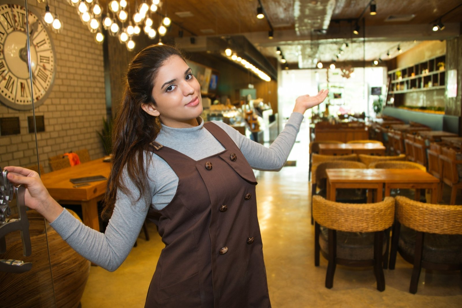 Funcionária de restaurante sorridente recebe clientes na entrada, simbolizando como o treinamento da equipe é essencial para garantir hospitalidade e um atendimento acolhedor.