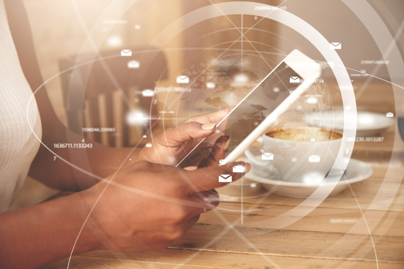 Close-up de mãos de uma pessoa segurando um tablet branco, com uma xícara de café ao fundo. Sobre a imagem, há uma sobreposição digital de ícones de e-mail flutuantes, linhas de conexão e um globo terrestre estilizado, simbolizando comunicação digital e conectividade global.
