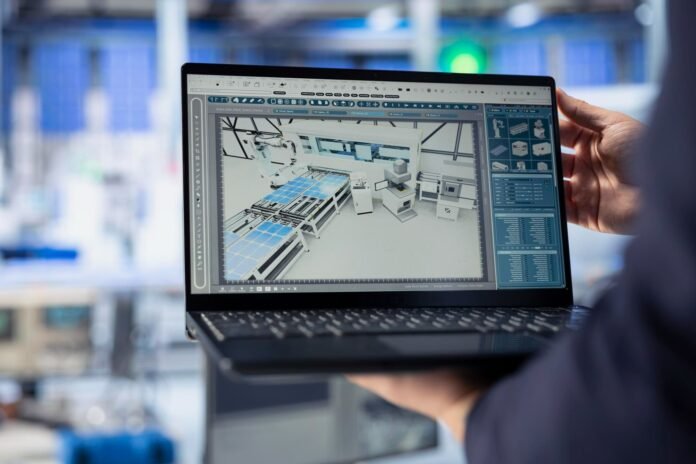 Uma pessoa segura um laptop em primeiro plano. A tela mostra um modelo 3D detalhado de uma instalação técnica com gráficos de análise, representando o uso da tecnologia do gêmeo digital.