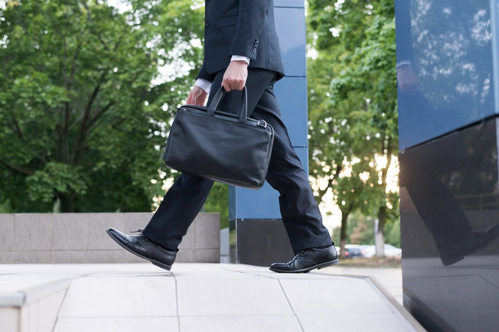 Homem vestindo roupa social e segurando uma pasta preta enquanto caminha. A foto sugere que ele está indo a uma reunião ou evento corporativo, a exemplo das rodadas de negócio às quais os assinantes do Portal do Hoteleiro poderão participar em São Paulo ao longo de 2026. 