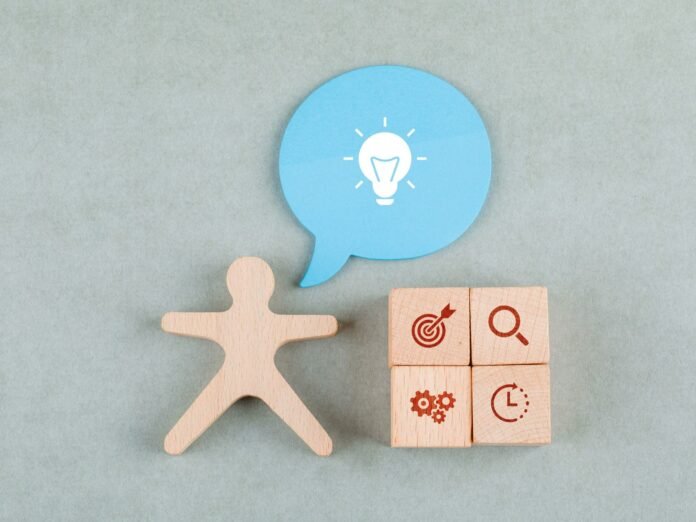 Imagem conceitual sobre governança na hotelaria. Uma figura de madeira representa o gestor associado a uma ideia (ícone de lâmpada). Ao lado, quatro blocos simbolizam os pilares da governança: estratégia (alvo), transparência (lupa), processos (engrenagens) e eficiência (relógio).