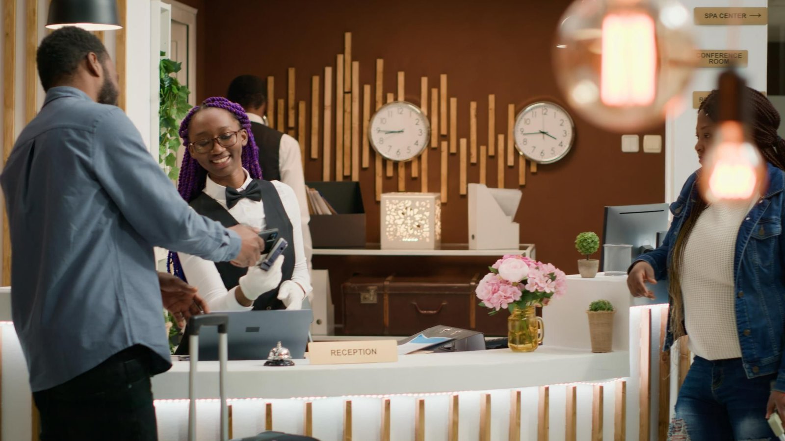 Hóspede realiza pagamento por aproximação via celular no balcão, ilustrando a agilidade no atendimento na recepção de hotel ao finalizar uma oferta de upselling personalizada.