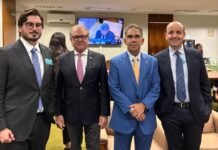 Fim da escala 6×1: ABIH-SP reforça articulação em Brasília e une hotelaria em defesa de diálogo técnico Fotografia em plano médio de quatro homens de terno, em pé e sorrindo, durante encontro que promoveu o debate acerca do fim da escala 6x1. Da esquerda para a direita estão: Leonardo Volpatti, da Volpatti Advogados Associados, vestindo terno cinza-escuro e óculos; Orlando de Souza, do FOHB, com terno preto e gravata cor-de-rosa; Sérgio Gaspar Pereira, da ABIH Nacional, com terno azul-claro; e Antonio Dias, da ABIH-SP, vestindo terno azul-marinho. Ao fundo vê-se um monitor de TV transmitindo uma sessão e parte de um sofá de couro.