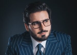 Retrato de meio-corpo do advogado Leonardo Volpatti, sócio-fundador do escritório Volpatti Advogados Associados e assessor jurídico da ABIH Nacional. Ele é um homem branco com barba bem aparada, usa óculos de grau com armação escura e veste um terno azul-marinho risca-de-giz sobre camisa branca e gravata com padrão de bolinhas. Fundo preto.