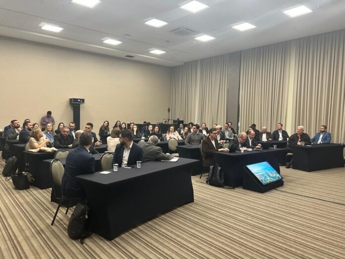 Vista panorâmica de uma sala de conferência lotada, repleta de profissionais de hotelaria sentados em mesas retangulares pretas, durante edição de junho do encontro de negócios do Portal do Hoteleiro, no Royal Palm Anhanguera, em Campinas (SP).