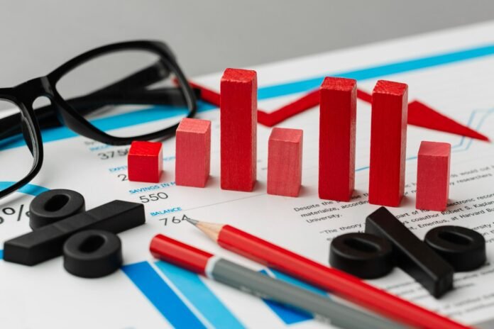 Mesa de escritório com ferramentas de análise de desempenho hoteleiro: relatórios impressos com gráficos financeiros, óculos de leitura, blocos vermelhos simulando um gráfico de barras para comparar métricas (como RevPAR ou ocupação), lápis e grandes símbolos de porcentagem simbolizando taxas de conversão e margens de lucro na gestão hoteleira.