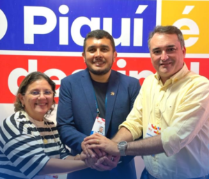 Três pessoas sorrindo para a foto, com as mãos sobrepostas no centro, simbolizando união. Da esquerda para a direita: Silvia Guimarães, usando blusa listrada; Alex Albuquerque (presidente da ABBTUR Nacional), de terno azul; e Ferdinando Lucena (à frente da Diretoria Executiva e de Estratégias da entidade), de camisa amarela. 