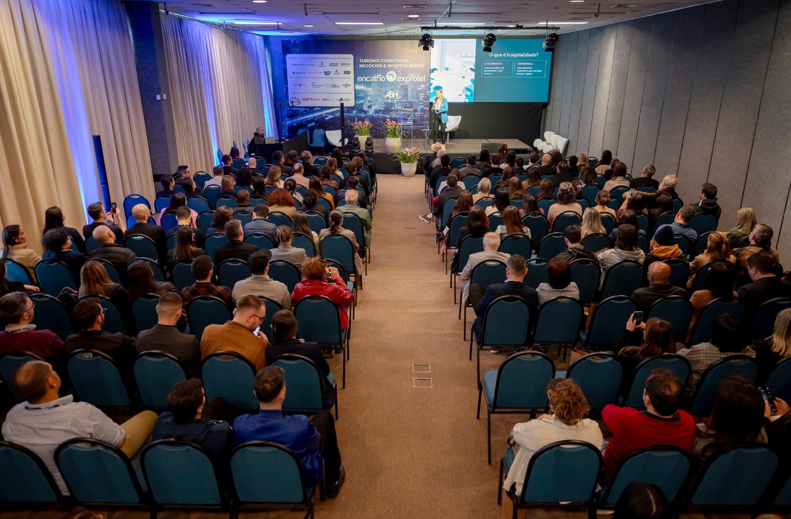 Auditório repleto de profissionais hoteleiros assistindo a uma apresentação sobre hospitalidade e negócios. Esta imagem exemplifica o nível das discussões técnicas que os participantes podem esperar na programação do 37º Encatho, em 2026.