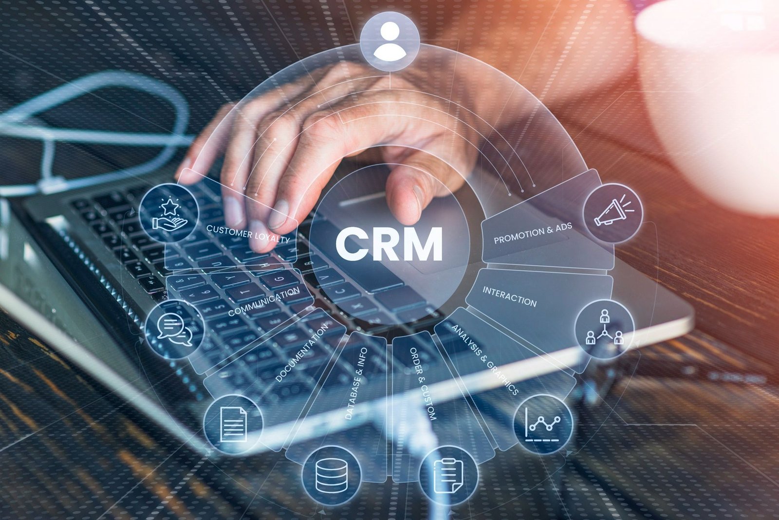 Imagem ilustrativa sobre tecnologia na hotelaria: mãos operando um notebook com uma interface digital sobreposta que exibe a sigla "CRM" ao centro, cercada por ícones representando comunicação, dados, lealdade do cliente e anúncios.