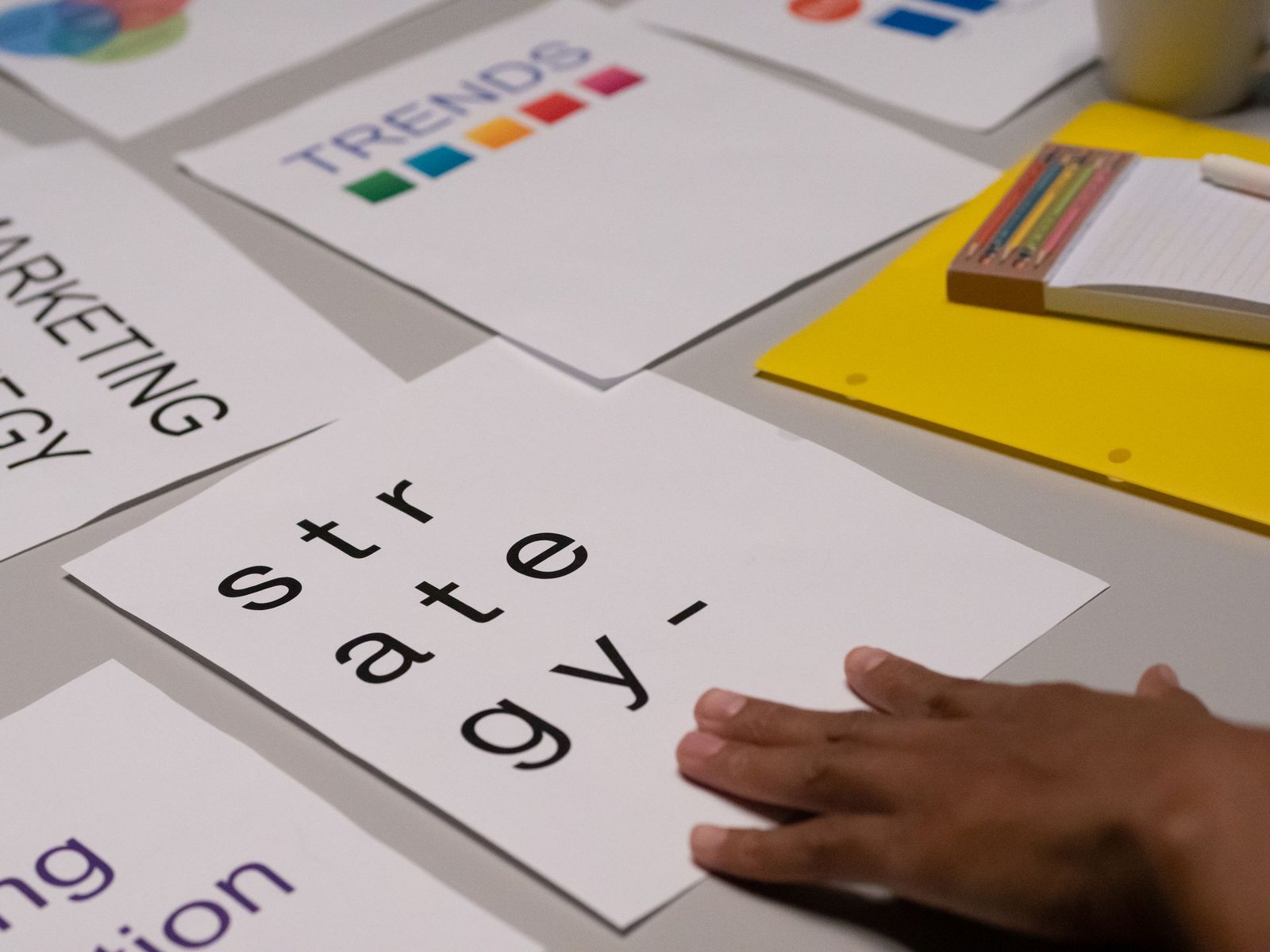 Mão de uma pessoa tocando um papel no qual está escrito 'strategy' ("estratégia"), representando o planejamento necessário para a entrega de um copywriting de qualidade.