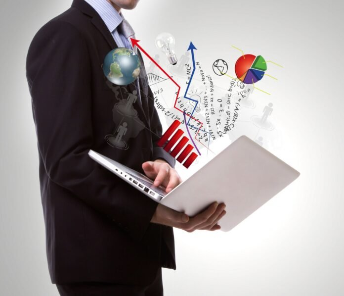 Homem de terno segurando um notebook aberto. Do computador saem gráficos coloridos, setas ascendentes, um globo terrestre, um gráfico de pizza e equações matemáticas flutuando sobre um fundo claro, ilustrando o conceito de precificação dinâmica.