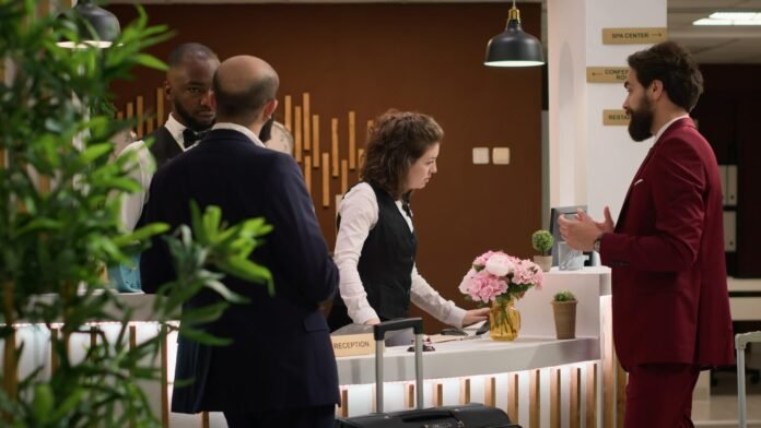 Equipe de recepção de hotel atende hóspedes no balcão, ilustrando a operação contínua do setor e os desafios de escalas diante da redução da jornada.